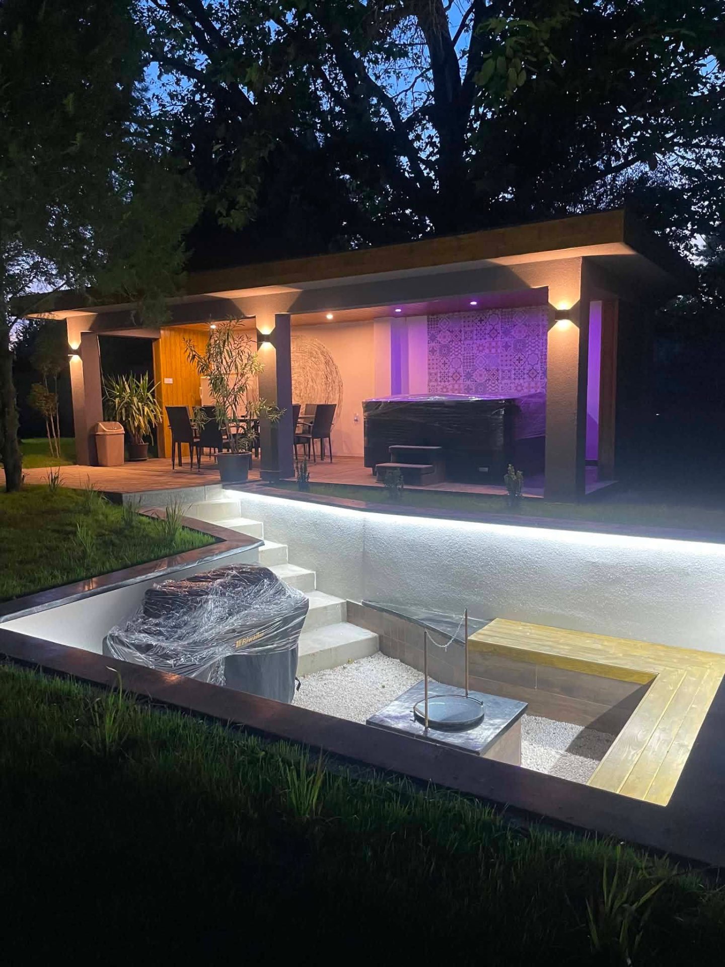 Kerti pavilon jacuzzival és süllyesztett tűzrakóhellyel este